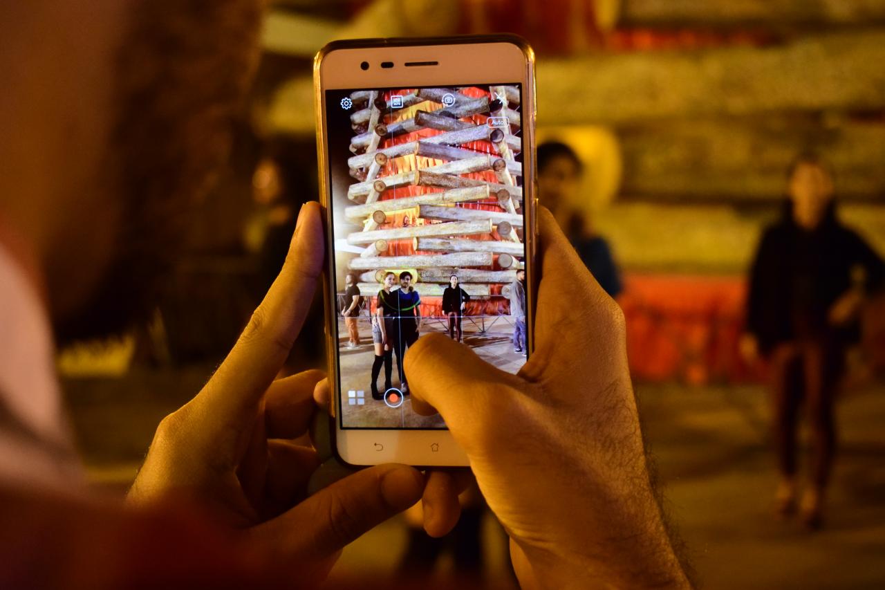 Turistas tirando fotos na réplica da fogueira de São João. 